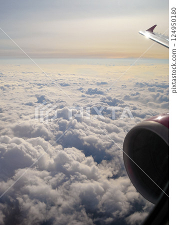 View of the clouds through the airplane window. Wing and turbine of a flying aircraft. The sky and the cloud. Travel, flight to fly 124950180