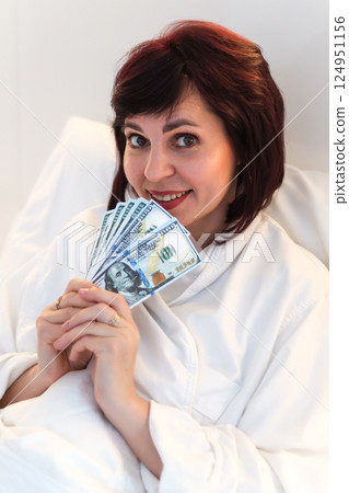 Dizzy with success, woman enjoys luxurious life and wealth while lying in bed 124951156