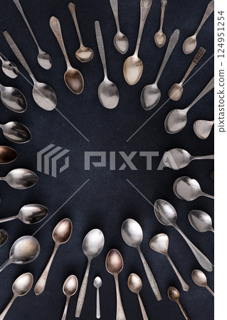 Set of different spoons. Silver cutlery on a black background. Spoon on the table 124951254