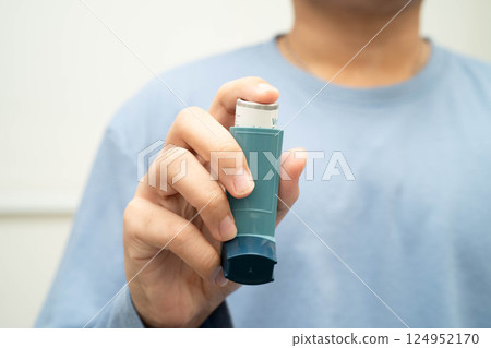 Asthma and chronic obstructive pulmonary disease COPD, Asian young man using metered dose inhaler MDI. Asthma and chronic obstructive pulmonary disease COPD, Asian young man using metered dose inhaler MDI. 124952170
