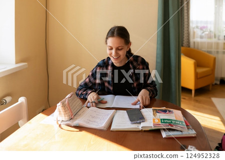 Student studying in a cozy room with books, notebook, and a phone on a sunny afternoon 124952328