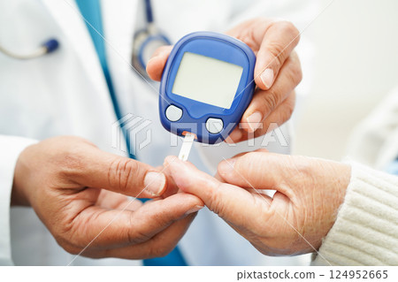 Asian doctor using digital glucose meter for check sample blood sugar level to treatment diabetes. Asian doctor using digital glucose meter for check sample blood sugar level to treatment diabetes. 124952665