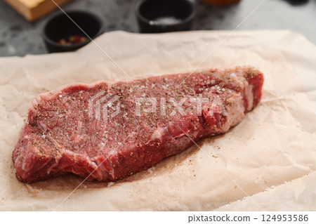 closeup raw seasoned new york steak on concrete countertop background 124953586