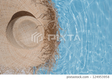 A girl with a straw hat with a large brim on the background of a blue pool. Sea, beach, vacation, sunscreen, warm weather, travel. High quality photo A girl with a straw hat with a large brim on the background of a blue pool. Sea, beach, vacation, sunscreen, warm weather, travel. High quality photo 124953958