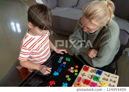 Child learning to count with wooden numbers and adult guidance at home 124954409