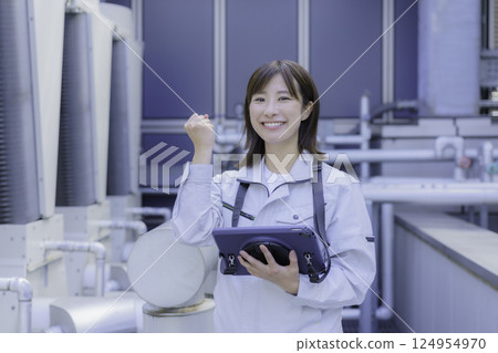 A smiling young female worker pumps her fist in the air while holding a tablet. Photo courtesy of Tokyo Electronics College, Denpa Gakuen Corporation 124954970