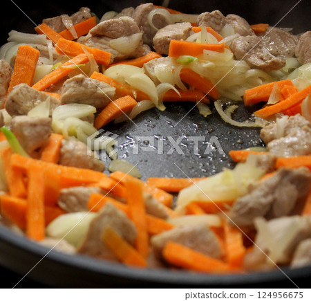 Steam rises above the frying pan from the frying meat with chopped onions and carrots 124956675