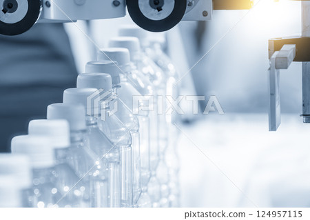 The full filled drinking water bottles  on the conveyor belt in the light blue scene. 124957115