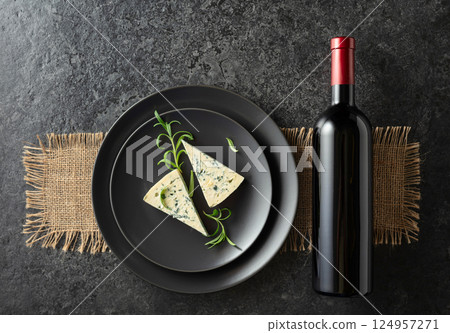 Bottle of red wine and blue cheese on a black plate. Bottle of red wine and blue cheese on a black plate. 124957271