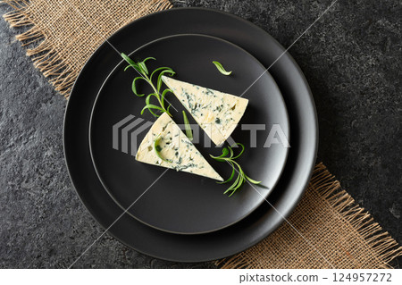 Blue cheese and rosemary on a black plate. 124957272