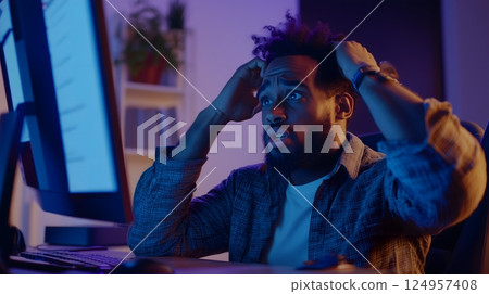 Shocked African American man reacting to computer error at night 124957408