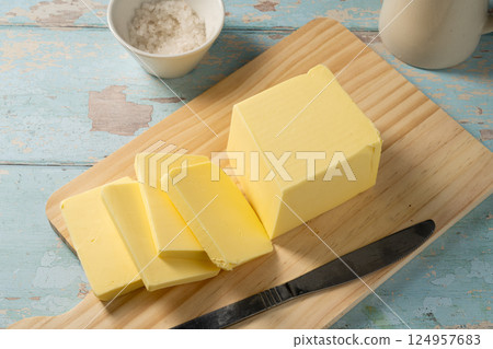 Butter block, grass-feed butter slices over wood cutting board. Vitamin D and source of fat  124957683