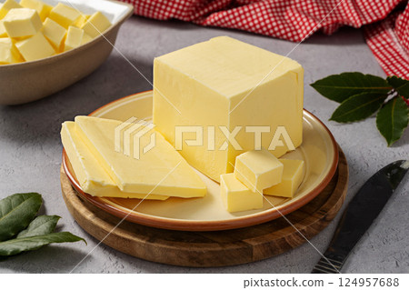 Butter block, grass-feed butter slices over wood cutting board. Vitamin D and source of fat Butter block, grass-feed butter slices over wood cutting board. Vitamin D and source of fat 124957688