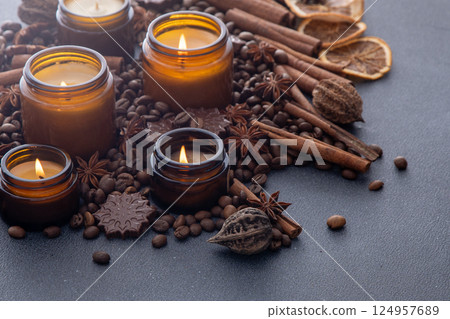 Soy scented candle in a jar. Coffee beans, anise, cinnamon spices. The candles are burning. Soy scented candle in a jar. Coffee beans, anise, cinnamon spices. The candles are burning. 124957689