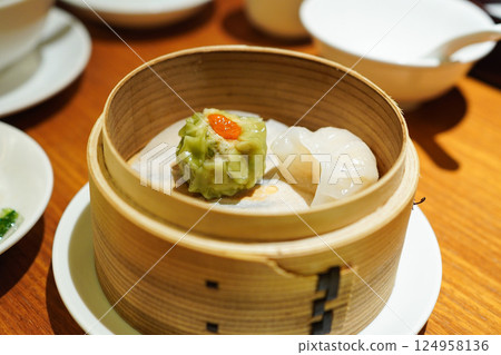 Spinach shumai and xiaolongbao served in steamer at a dim sum restaurant 124958136