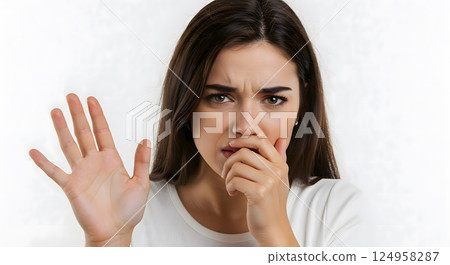 Worried european woman with long brown hair raising hand and covering mouth 124958287