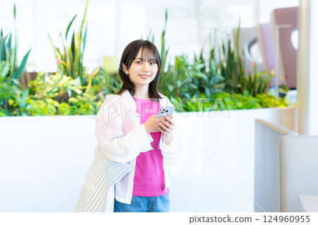 一個微笑的女人看著智能手機 一個微笑的女人看著智能手機 124960955