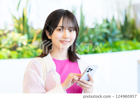 A smiling woman looking at a smartphone A smiling woman looking at a smartphone 124960957
