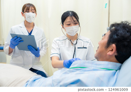 A female nurse checking the vital signs of an inpatient in a hospital ward A female nurse checking the vital signs of an inpatient in a hospital ward 124961009