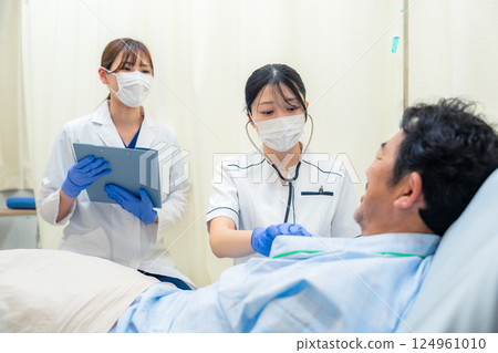A female nurse checking the vital signs of an inpatient in a hospital ward 124961010