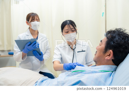 A female nurse checking the vital signs of an inpatient in a hospital ward 124961019