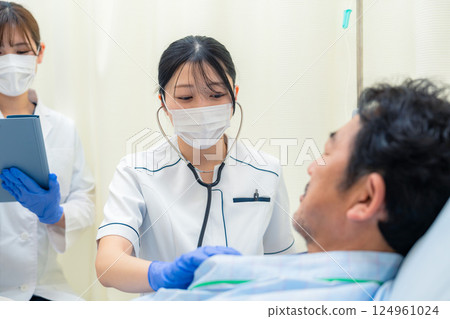 一名女護士在醫院病房檢查住院病人的生命徵象 一名女護士在醫院病房檢查住院病人的生命徵象 124961024