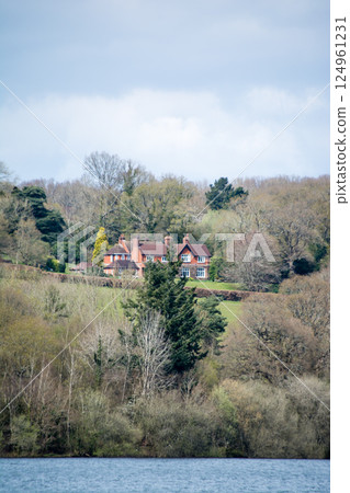 A historic brick building surrounded by evergreens and sparsely populated brown trees on a hill in a town on the outskirts of London A historic brick building surrounded by evergreens and sparsely populated brown trees on a hill in a town on the outskirts of London 124961231