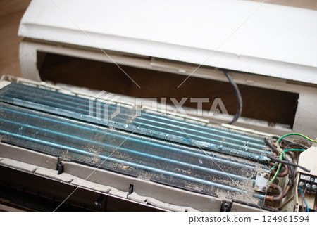 Dirty and disassembled wall-mounted air conditioner unit, showing internal components and dust. repair or cleaning. 124961594
