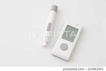 Blood glucose meter and lancet pen on white background, used for diabetes monitoring and blood sugar level testing. 124961601