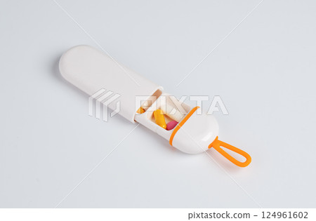 Portable pill case with colorful capsules and tablets inside, isolated on white background 124961602