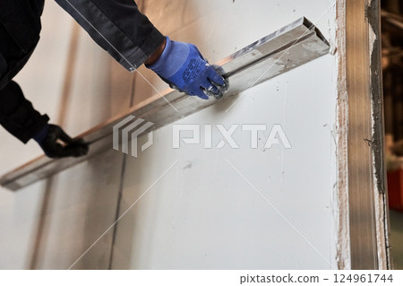 Close-up of the wall alignment rule tool. A man is smoothing a layer of plaster on a wall. With space to copy. High quality photo Close-up of the wall alignment rule tool. A man is smoothing a layer of plaster on a wall. With space to copy. High quality photo 124961744