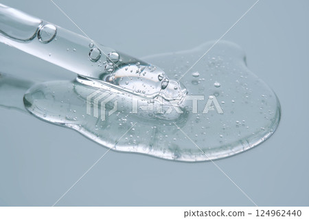 Pipette with serum on a blue background. Product texture. 124962440