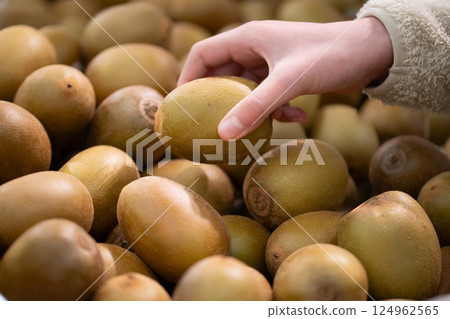 Shopper's hands choosing kiwi fruit 124962565