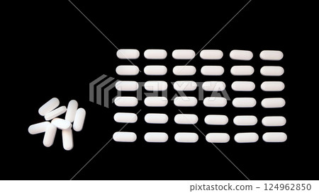 Oval white supplement tablets, arranged neatly in rows, with a small pile on the left. With black background. Oval white supplement tablets, arranged neatly in rows, with a small pile on the left. With black background. 124962850