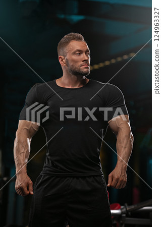 athletic man stands proudly in gym exhibiting impressive muscle definition and strength. He appears focused and confident ready engage in challenging workout routine. 124963327
