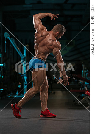 muscular man displays his strength and dedication in fitness studio captured during evening workout session. Focused on training he highlights his well defined physique. muscular man displays his strength and dedication in fitness studio captured during evening workout session. Focused on training he highlights his well defined physique. 124963332