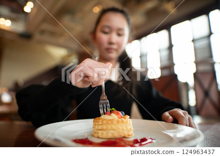 Girl eating sweets at cafe 124963437