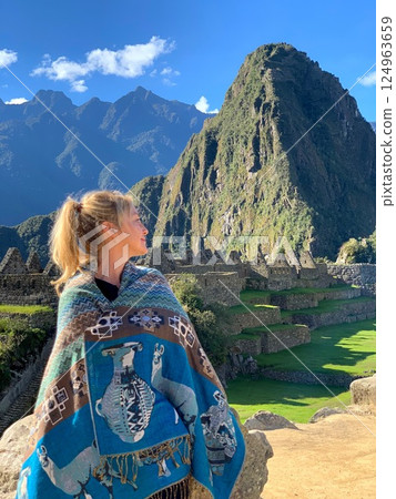 Woman in peruvian poncho looking on Machu Picchu Peru Woman in peruvian poncho looking on Machu Picchu Peru 124963659