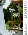 A wedding arch with vibrant flowers and candles on a lovely patio 124963794
