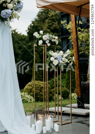 A wedding arch with vibrant flowers and candles on a lovely patio A wedding arch with vibrant flowers and candles on a lovely patio 124963794