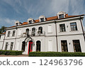 A large white building features a striking red door and roof 124963796