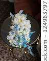 A bouquet of delicate white and blue flowers sits elegantly on a table 124963797