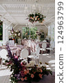 A large room with tables, chairs, and a vase of flowers 124963799