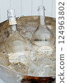 Two bottles of wine are resting comfortably in a bucket filled with ice 124963802