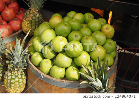 A selection of Fresh Green Apples alongside Pineapples at a Fruit Stand A selection of Fresh Green Apples alongside Pineapples at a Fruit Stand 124964071