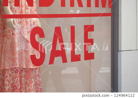 Large red Sale text letters on a glass wall obstruct a view inside the popular fashion store Large red Sale text letters on a glass wall obstruct a view inside the popular fashion store 124964122