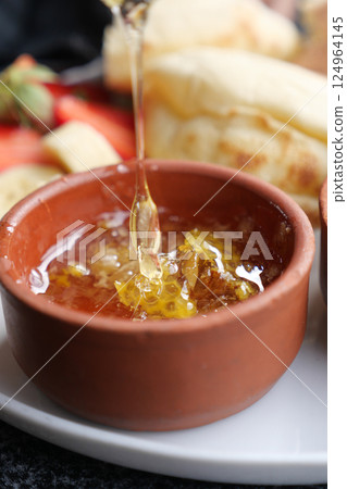 Golden Honey Drizzling Luxuriously in a Rustic Clay Dish with Fresh Fruits Golden Honey Drizzling Luxuriously in a Rustic Clay Dish with Fresh Fruits 124964145