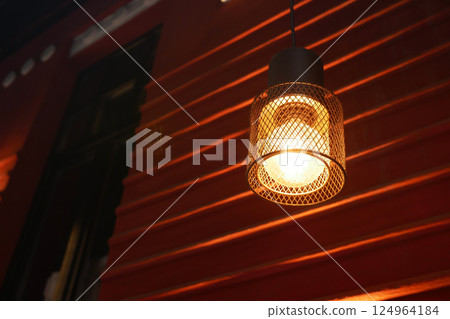 A Stylish Hanging Light that Emits a Warm Glow against a Red Wall A Stylish Hanging Light that Emits a Warm Glow against a Red Wall 124964184