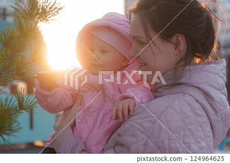 Mother embraces daughter while enjoying sunset at urban playground during golden hour 124964625