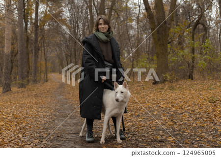 woman in an autumn park on a morning walk with her dog woman in an autumn park on a morning walk with her dog 124965005